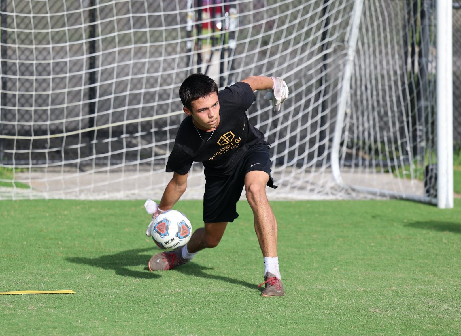 Goalkeeper scooping a ground-level ball — visual tracking in action